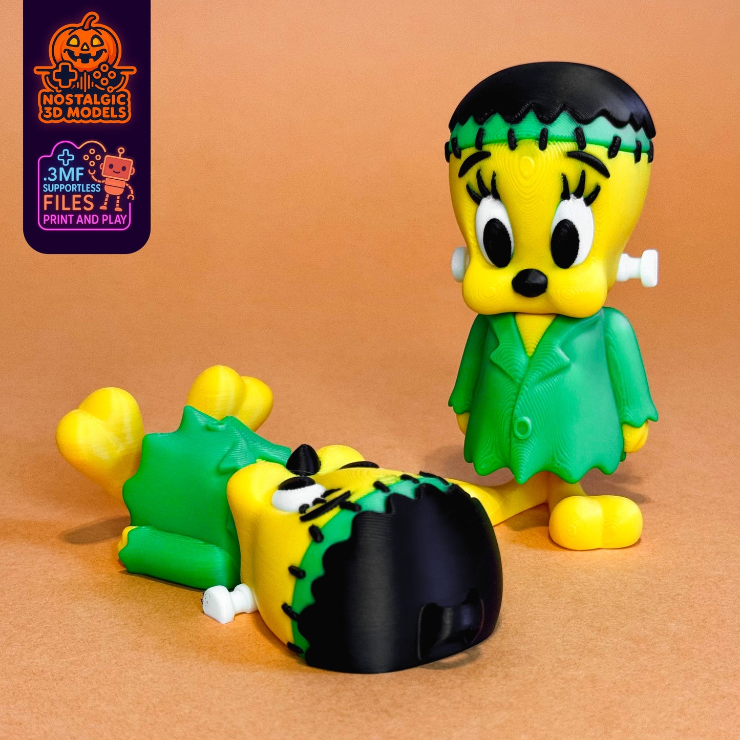Two 3D printed FrankenTweety figures: one standing confidently, the other playfully laying on its back. Both feature Halloween-themed green and yellow Frankenstein outfits with stitched hair and bolts
