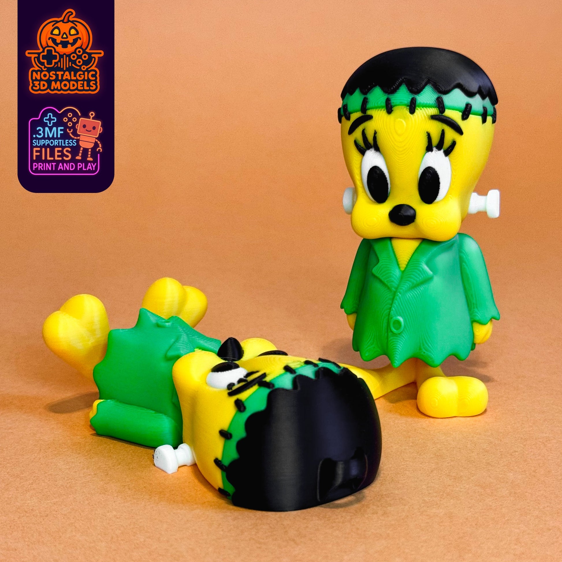 Two 3D printed FrankenTweety figures: one standing confidently, the other playfully laying on its back. Both feature Halloween-themed green and yellow Frankenstein outfits with stitched hair and bolts