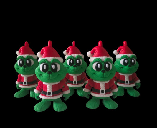 Five small 3D-printed Grinch ornaments wearing red Santa outfits and hats, arranged in a row against a solid black background. Each figure is bright green with big cartoon eyes and a festive Christmas design.