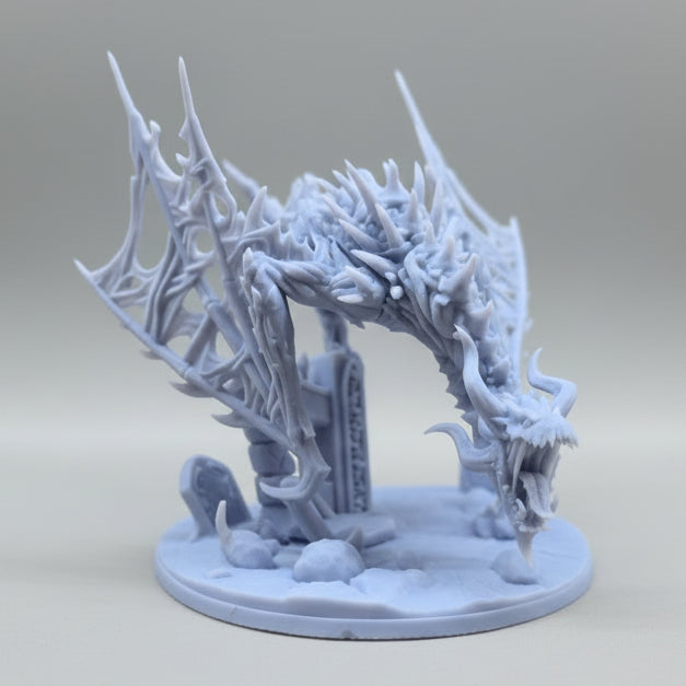 Side view of an unpainted resin dragon arch miniature showing twisted body, webbed skeletal wings, and rocky base.