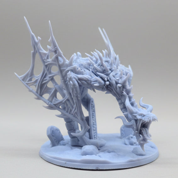 Rear-angle view of an unpainted resin dragon arch miniature highlighting wing structure, tail details, and scenic base.