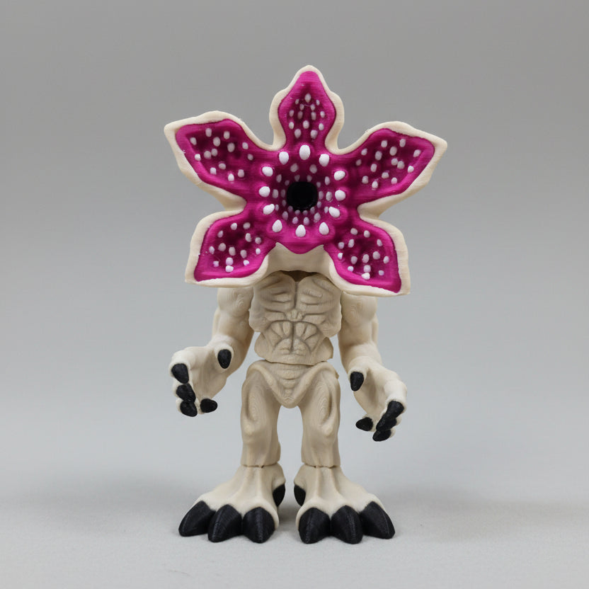 Front view of a filament 3D printed mind flayer–inspired miniature with a pale bone-coloured body, black claws, and a large open pink flower-shaped head with detailed inner petal texture, displayed on a neutral background.