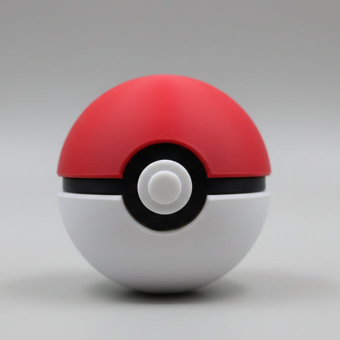 Front view of a 3D printed Pokéball with red top, white base, black centre band, and raised white button, displayed against a neutral background.