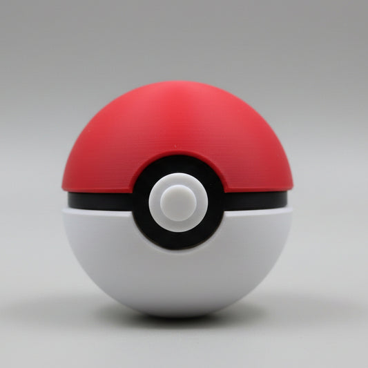 Front view of a 3D printed Pokéball with red top, white base, black centre band, and raised white button, displayed against a neutral background.