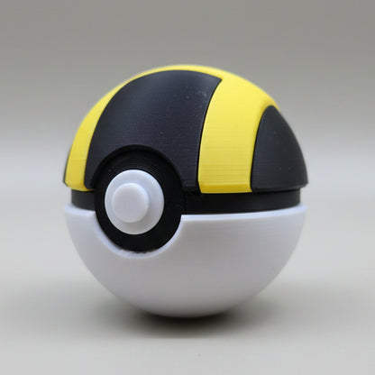 Angled view of a 3D printed Ultra Ball featuring a black and yellow top, white bottom half, and detailed centre button on a neutral backdrop.