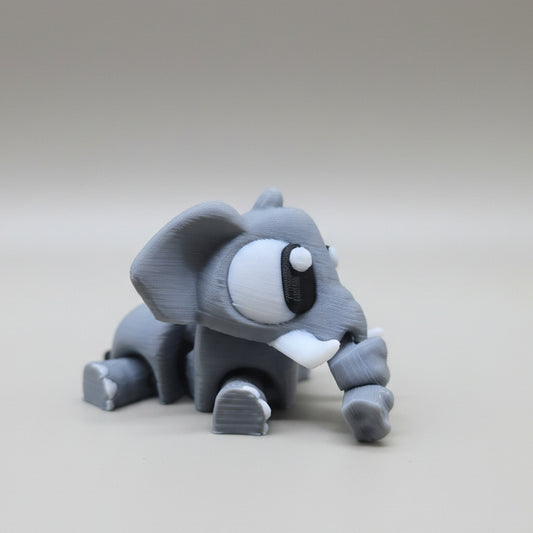 Side view of a grey 3D printed elephant figurine with a curled trunk and cartoon-style eyes