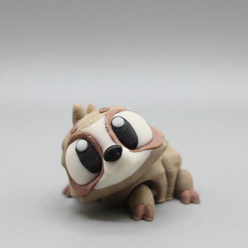 Cute 3D printed flexi sloth figure featuring brown and cream colouring, large expressive eyes, tiny claws, and an adorable relaxed pose. A flexible articulated animal collectible and fidget toy photographed on a grey background.