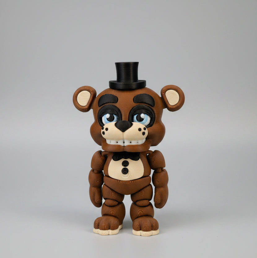 Front view of a 3D printed Freddy Fazbear flexi figure inspired by Five Nights at Freddy’s, featuring a brown animatronic bear with articulated limbs, black top hat, bow tie, blue eyes, button details, and a toothy grin, photographed against a clean light background.