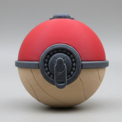 Front view of a 3D printed Hisuian Poké Ball featuring a red top, textured tan base, and detailed grey mechanical latch centered on the front, displayed on a plain background.