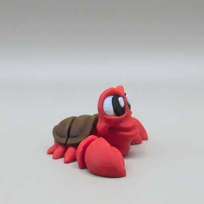 Side view of a red Sebastian flexi crab figure showing articulated body and shell