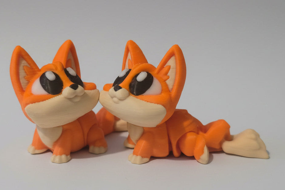 Two orange and beige fox figurines on a gray background