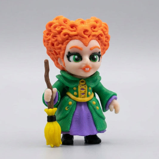 3D printed Winifred Sanderson figurine inspired by Disney's Hocus Pocus, featuring bright orange curly hair, large green eyes, a detailed green coat, purple dress and yellow broomstick, standing against a clean light grey background.